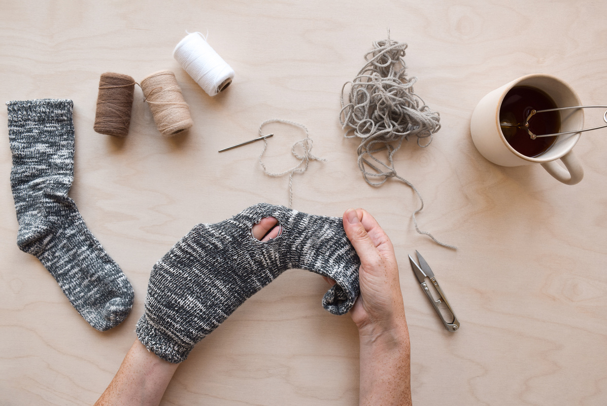 Woman's hands holding sock with a hole to be fixed